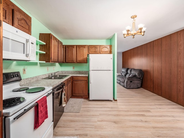 kitchen with sink, light wood-type flooring, a notable chandelier, pendant lighting, and white appliances