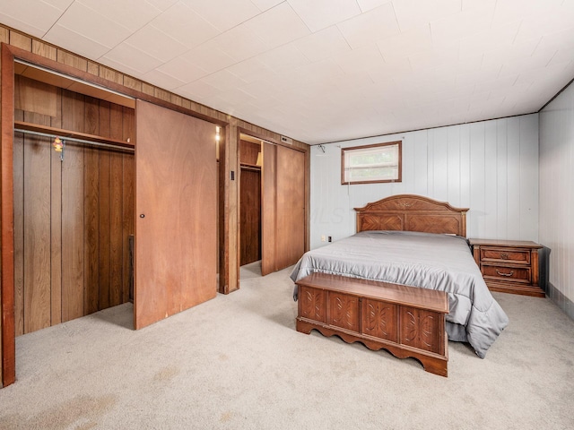 carpeted bedroom featuring wood walls