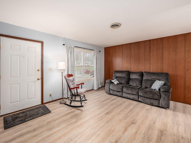 living room featuring light hardwood / wood-style floors and wood walls