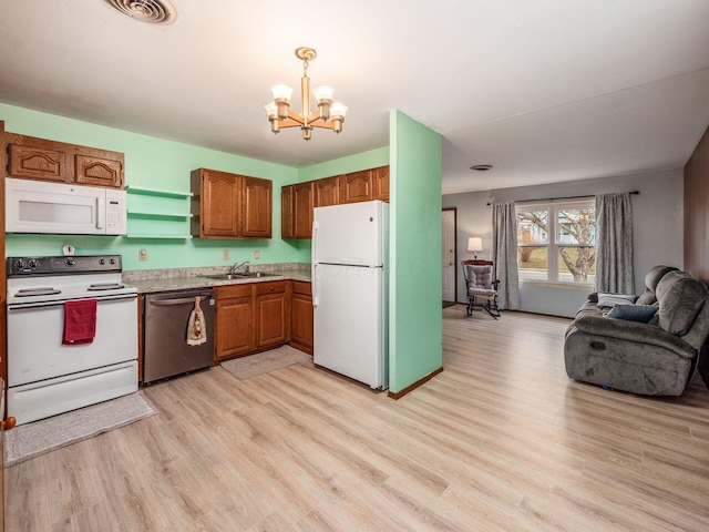 kitchen featuring sink, an inviting chandelier, decorative light fixtures, light wood-type flooring, and white appliances