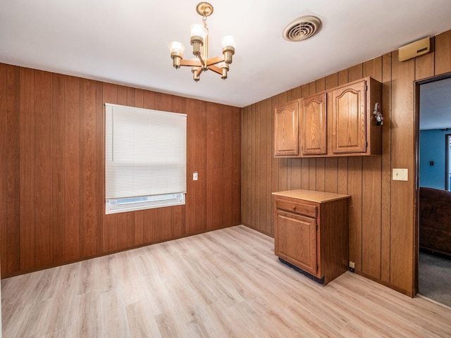 kitchen featuring decorative light fixtures, wood walls, a chandelier, and light hardwood / wood-style flooring