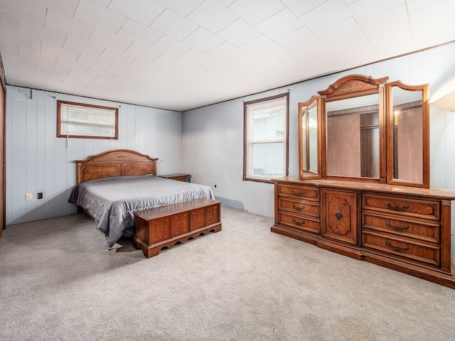 bedroom with light carpet and wood walls