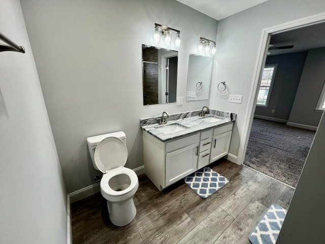 bathroom featuring hardwood / wood-style flooring, vanity, toilet, and a shower