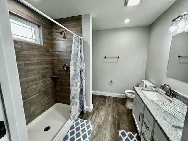 bathroom featuring hardwood / wood-style floors, vanity, a shower with curtain, toilet, and a textured ceiling