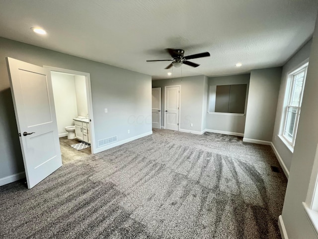 unfurnished bedroom with ensuite bath, ceiling fan, light carpet, and a textured ceiling