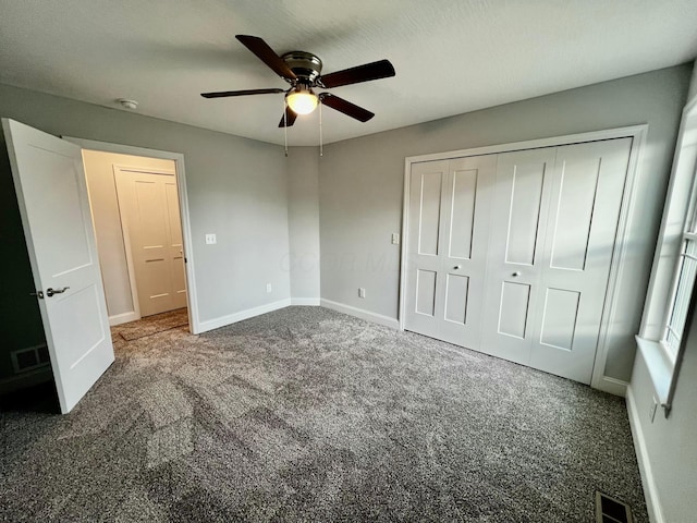 unfurnished bedroom featuring dark colored carpet, a closet, and ceiling fan