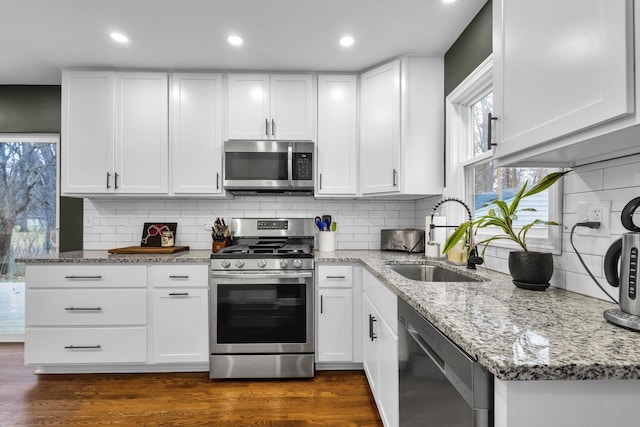 kitchen with dark wood-type flooring, white cabinets, sink, tasteful backsplash, and stainless steel appliances