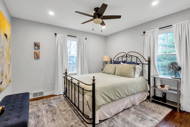 bedroom with hardwood / wood-style floors, ceiling fan, and multiple windows