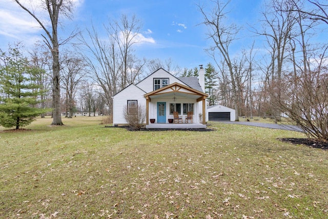 view of front of house featuring a porch, a garage, a front lawn, and an outdoor structure