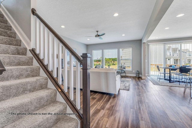 staircase with hardwood / wood-style flooring and ceiling fan