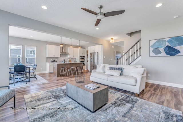 living room with ceiling fan, wood-type flooring, and a textured ceiling