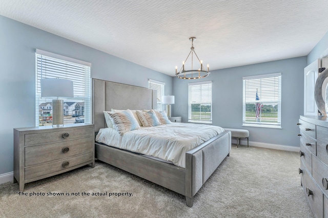 bedroom featuring light carpet, a textured ceiling, and a notable chandelier