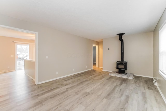 unfurnished living room with light wood-type flooring and a wood stove