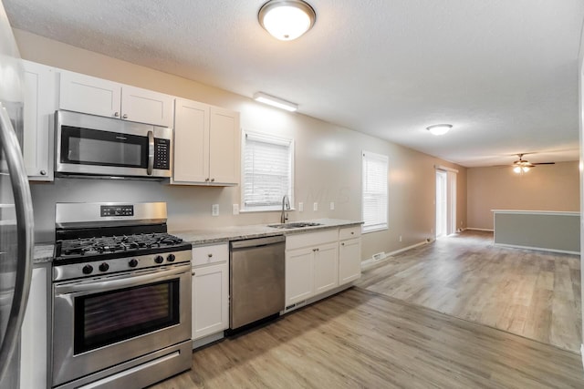 kitchen with sink, white cabinets, light hardwood / wood-style flooring, and appliances with stainless steel finishes