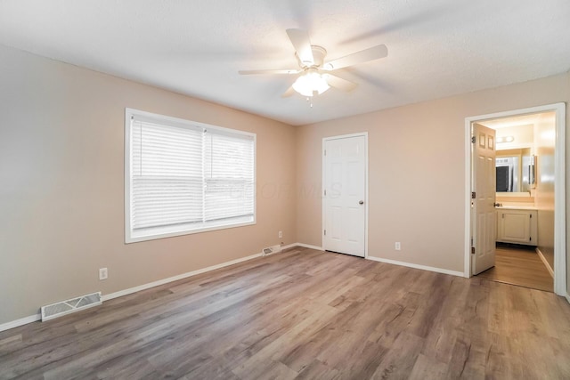 unfurnished bedroom with connected bathroom, light hardwood / wood-style floors, and ceiling fan