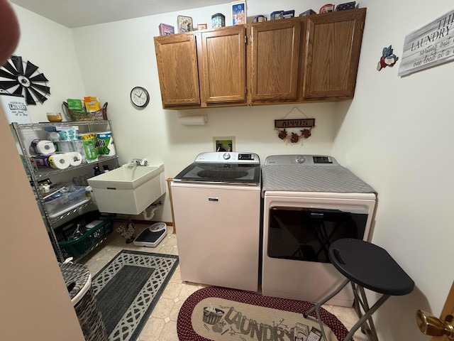 clothes washing area featuring washing machine and dryer, sink, and cabinets