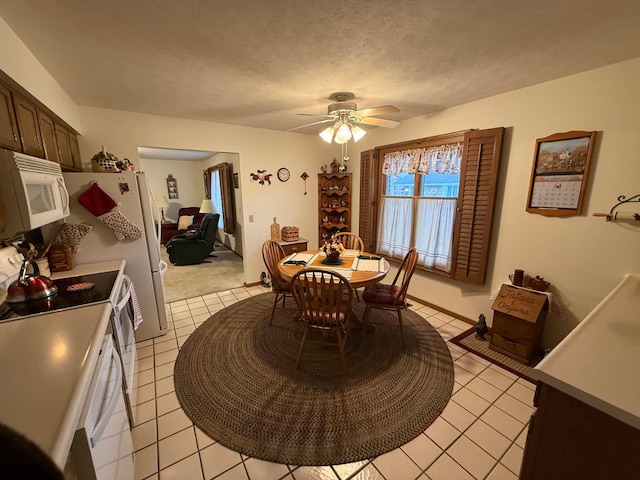 tiled dining space with ceiling fan and a textured ceiling