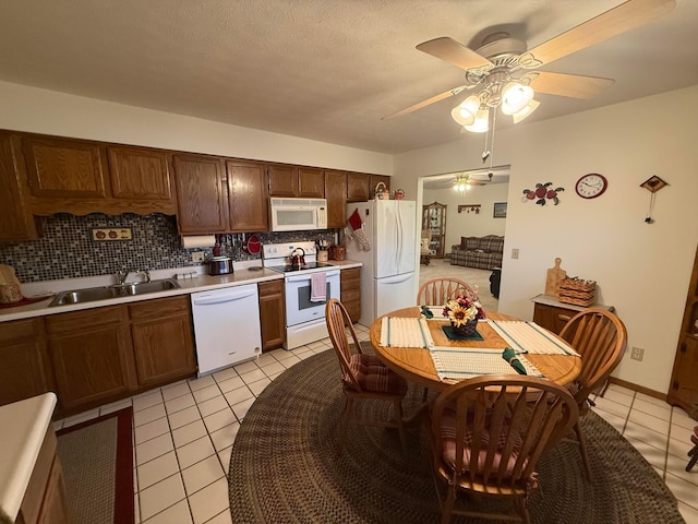 kitchen with decorative backsplash, white appliances, light tile patterned flooring, and sink