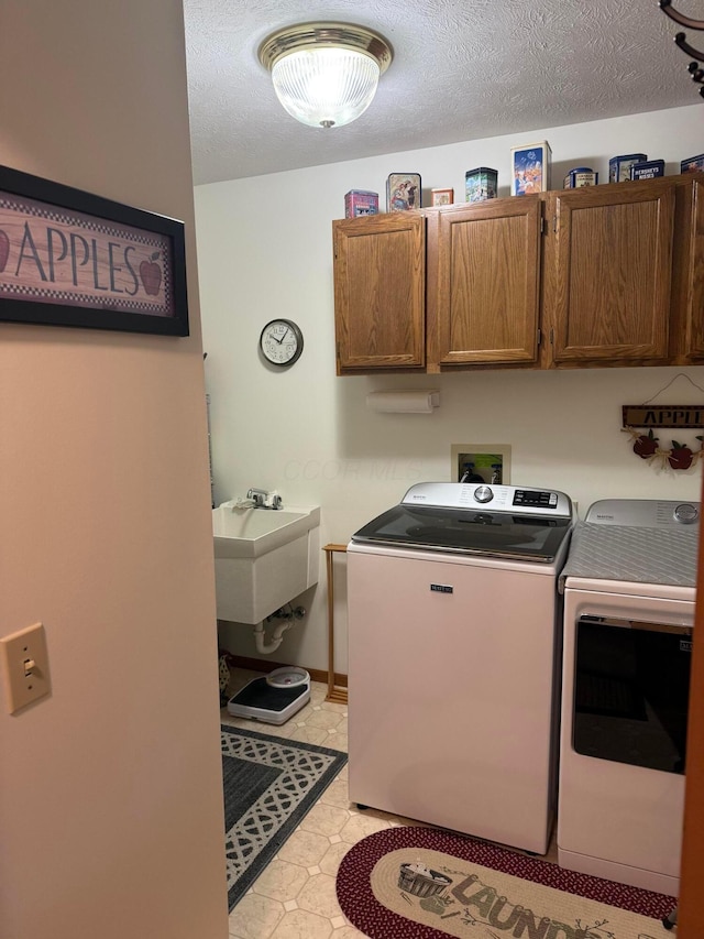 laundry room featuring separate washer and dryer, sink, cabinets, and a textured ceiling