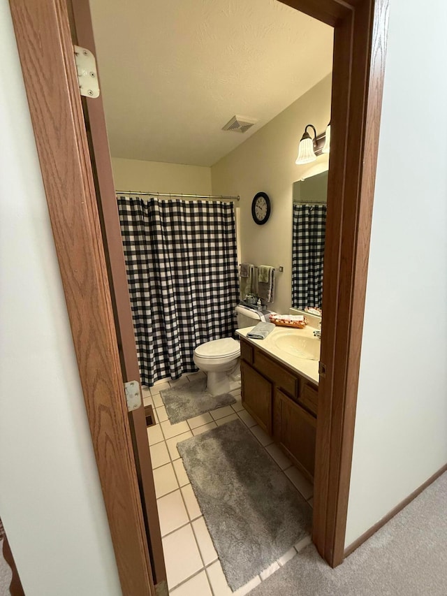 bathroom with tile patterned floors, vanity, toilet, and a textured ceiling