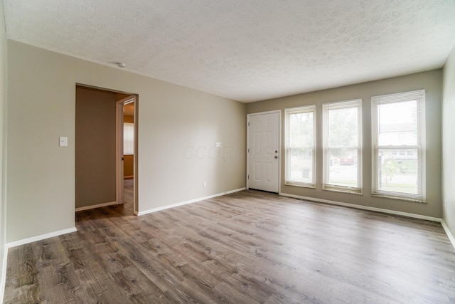 spare room with dark hardwood / wood-style floors and a textured ceiling