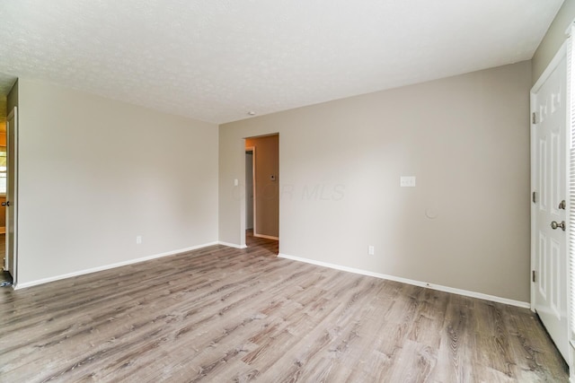 unfurnished room with light wood-type flooring and a textured ceiling