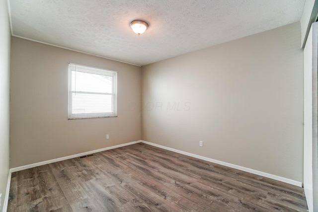 spare room featuring a textured ceiling and dark wood-type flooring