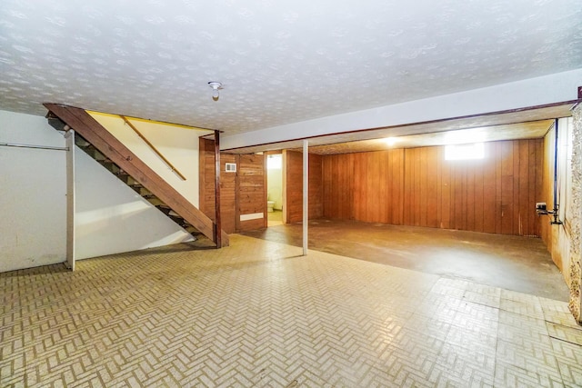 basement featuring a textured ceiling and wood walls