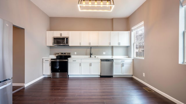 kitchen with dark hardwood / wood-style floors, sink, white cabinetry, and stainless steel appliances