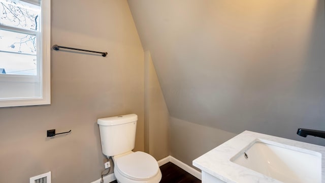 bathroom featuring hardwood / wood-style floors, vanity, toilet, and lofted ceiling