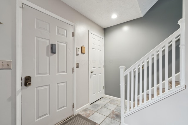 entryway featuring light tile patterned floors and a textured ceiling