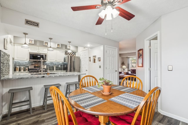 dining space with a textured ceiling, dark hardwood / wood-style floors, ceiling fan, and sink