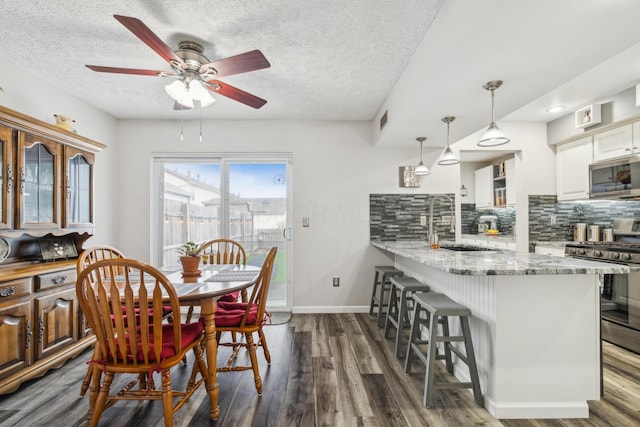 dining space with a textured ceiling, ceiling fan, dark hardwood / wood-style flooring, and sink