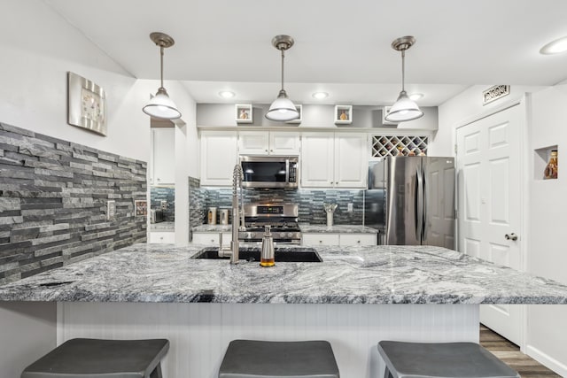 kitchen featuring light stone countertops, stainless steel appliances, backsplash, pendant lighting, and white cabinets