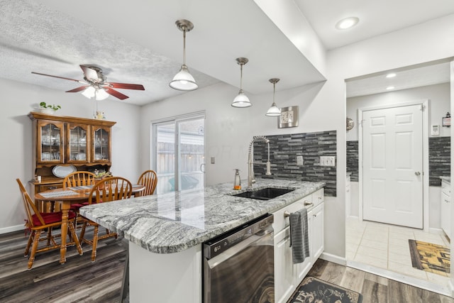 kitchen featuring tasteful backsplash, white cabinetry, sink, and stainless steel dishwasher