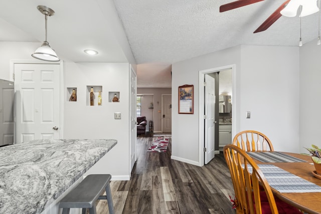 dining area with a textured ceiling, ceiling fan, and dark wood-type flooring