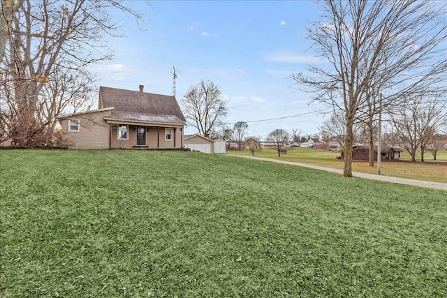 view of yard featuring an outbuilding, a porch, and a garage