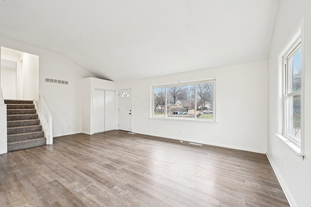 unfurnished living room with hardwood / wood-style floors and vaulted ceiling