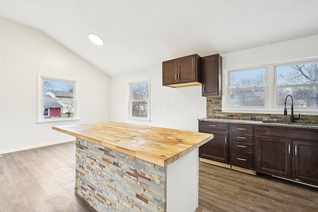 kitchen featuring butcher block countertops, sink, dark wood-type flooring, and lofted ceiling