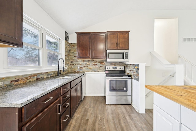 kitchen featuring light wood-type flooring, tasteful backsplash, stainless steel appliances, sink, and lofted ceiling