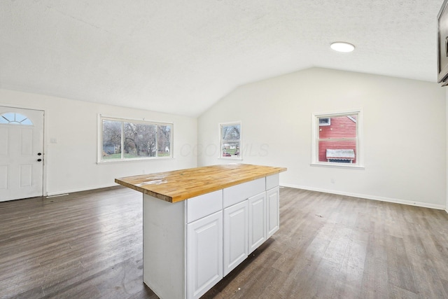 kitchen featuring wooden counters, a textured ceiling, vaulted ceiling, dark wood-type flooring, and white cabinetry