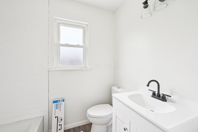 bathroom featuring hardwood / wood-style floors, vanity, toilet, and a bathing tub