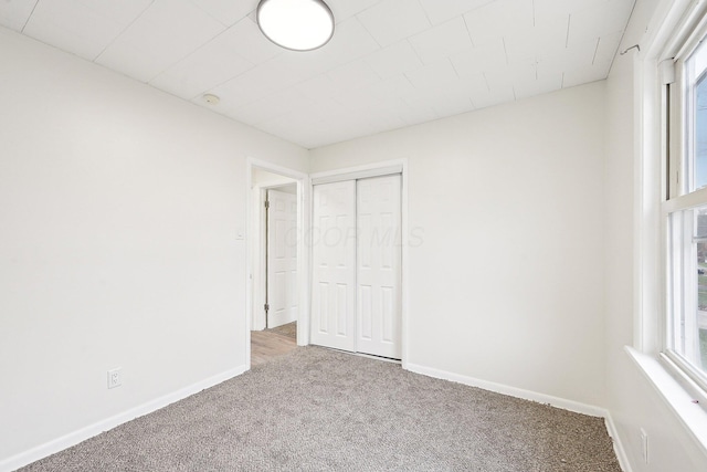 unfurnished bedroom with carpet flooring, a closet, and multiple windows