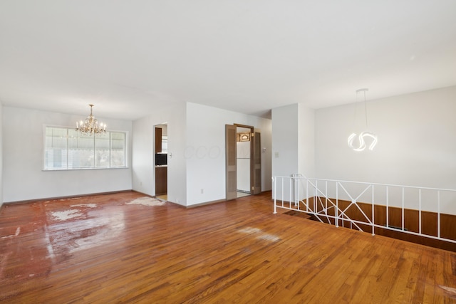 unfurnished room with a notable chandelier and wood-type flooring