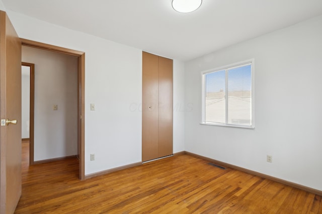 unfurnished bedroom featuring light wood-type flooring and a closet