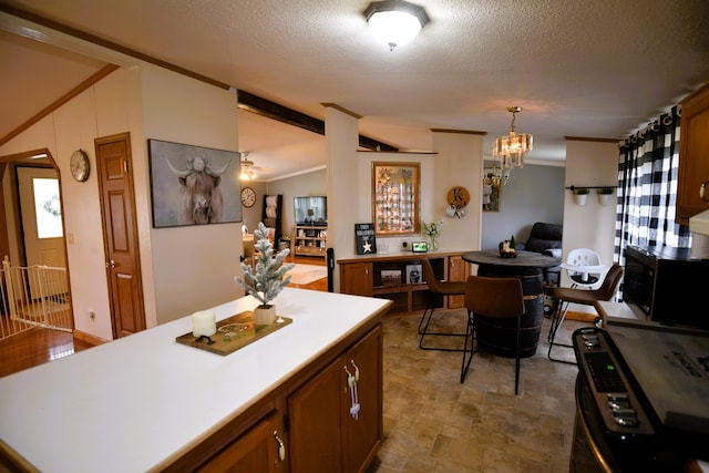 kitchen featuring a center island, lofted ceiling, ceiling fan with notable chandelier, hanging light fixtures, and a textured ceiling