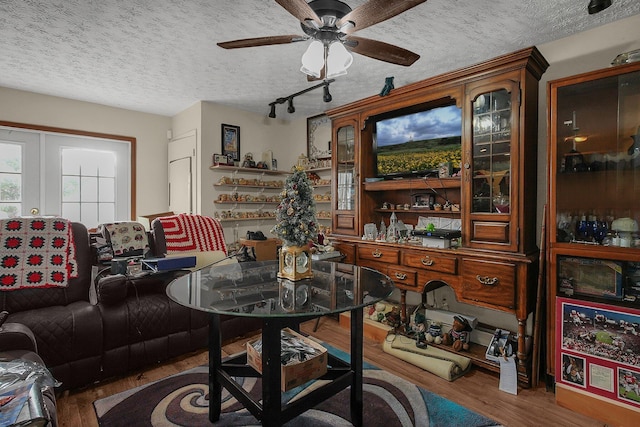 dining room with hardwood / wood-style flooring, ceiling fan, a textured ceiling, and french doors