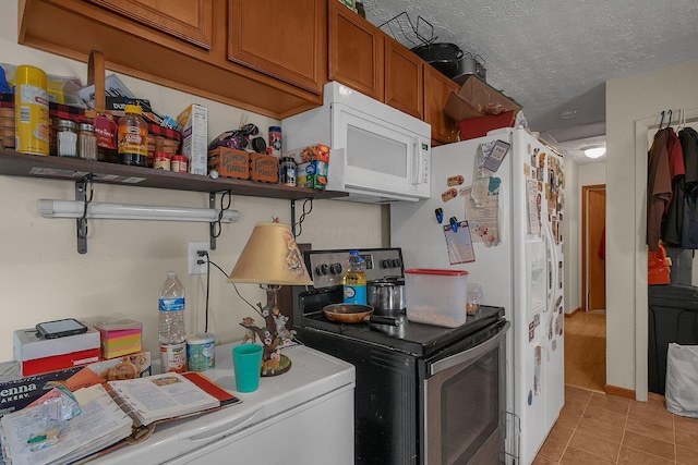 kitchen featuring stainless steel range with electric stovetop, light tile patterned floors, and a textured ceiling