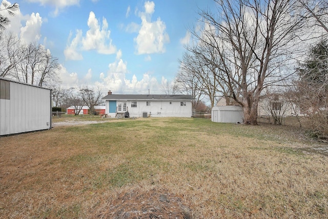 rear view of house with a shed and a yard