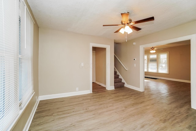 unfurnished room with ceiling fan, light hardwood / wood-style flooring, and a textured ceiling